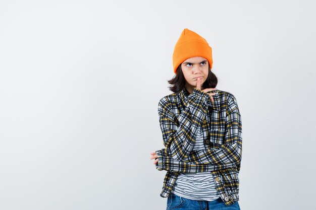 Teen woman in checkered shirt and beanie gesticulating isolated