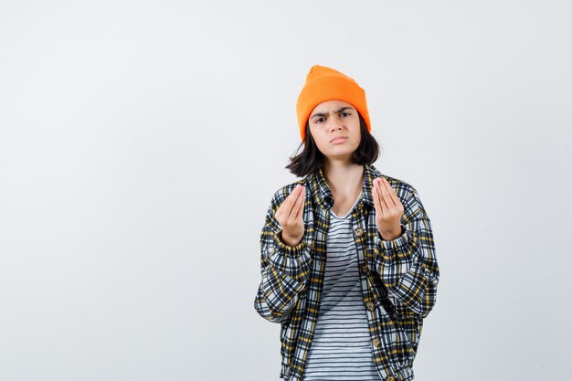 Teen woman in checkered shirt and beanie gesticulating isolated