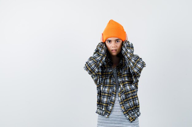 Teen woman in checkered shirt and beanie gesticulating isolated