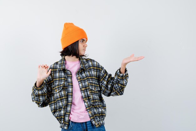 Teen woman pretending to show something in t-shirt looking focused