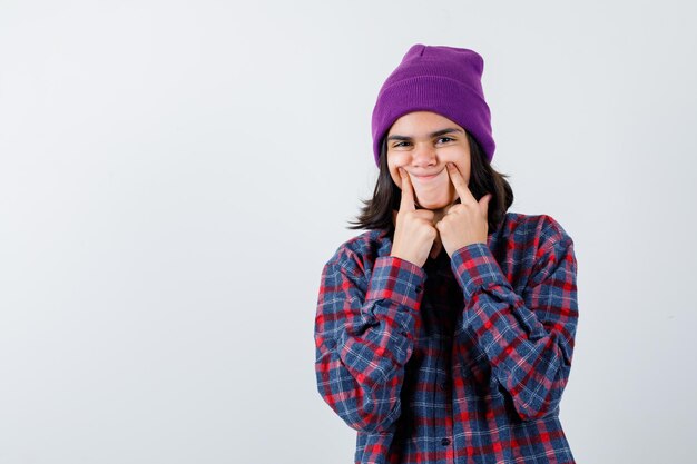 Teen woman putting index finger near mouth forcing smile