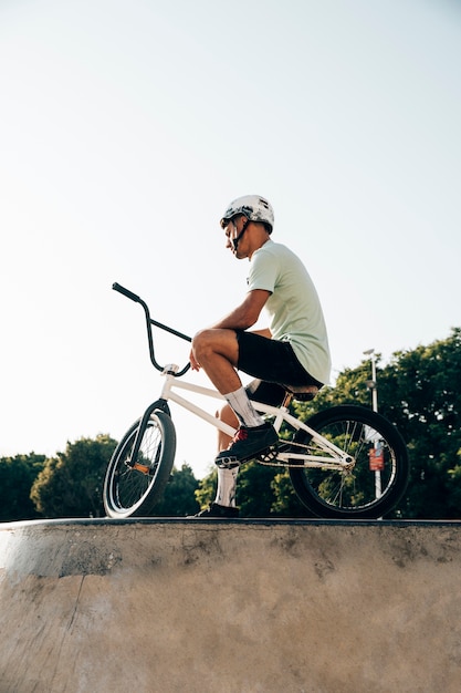 Free photo teenage bmx rider standing with his bike low angle view