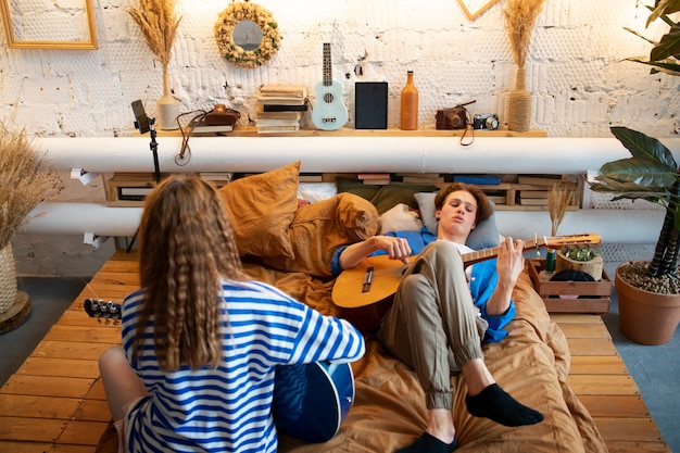 Free photo teenage boy and girl recording music at their home studio with guitar