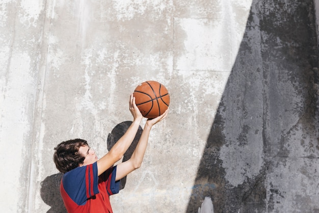 Free Photo teenage boy practicing basketball in front of wall