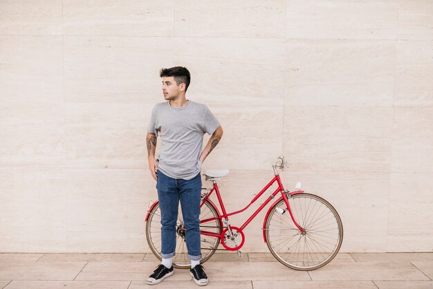 Teenage boy standing in front of bicycle on pavement