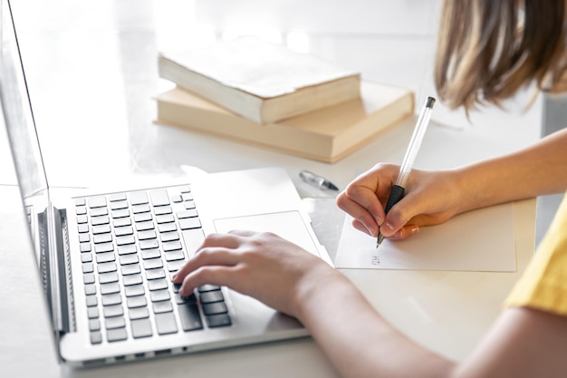 Free Photo a teenage girl does her homework while sitting with books and a laptop