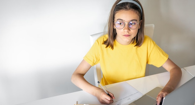 Free photo a teenage girl does her homework while sitting with books and a laptop