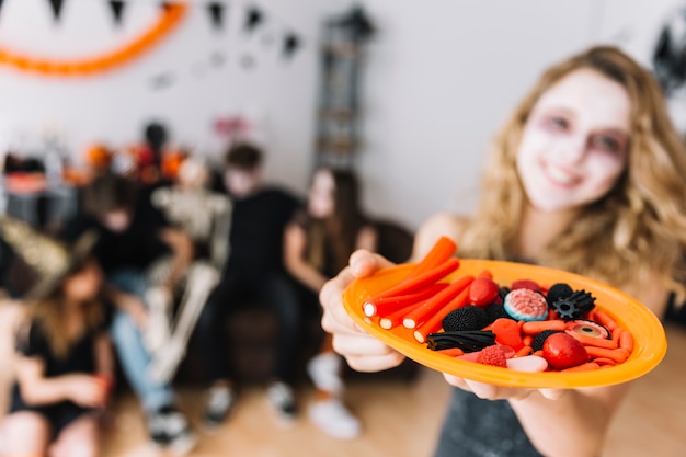 Free Photo teenage girl on halloween party giving plate with marmalade