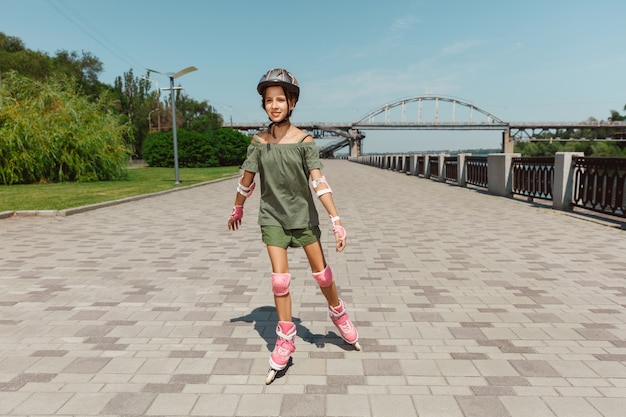 Teenage girl in a helmet learns to ride on roller skates outdoors