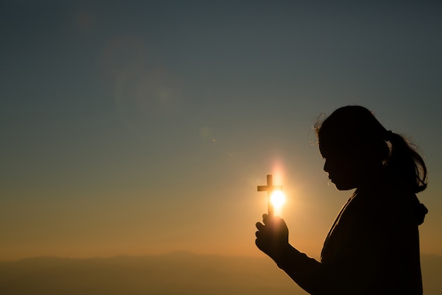 Free photo teenage girl holding cross with praying. peace, hope, dreams concept.