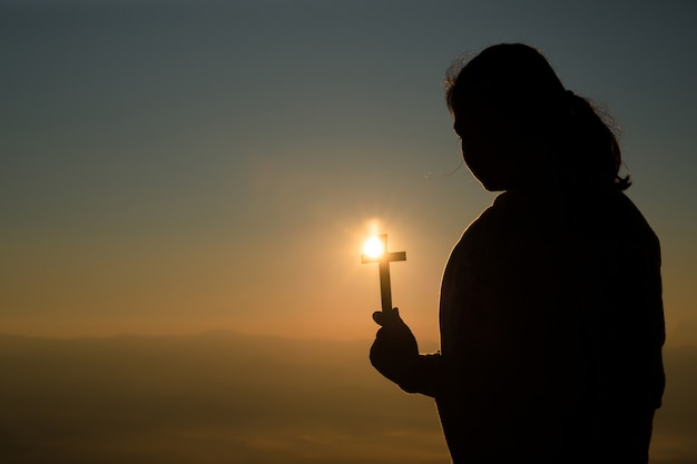 Free photo teenage girl holding cross with praying. peace, hope, dreams concept.