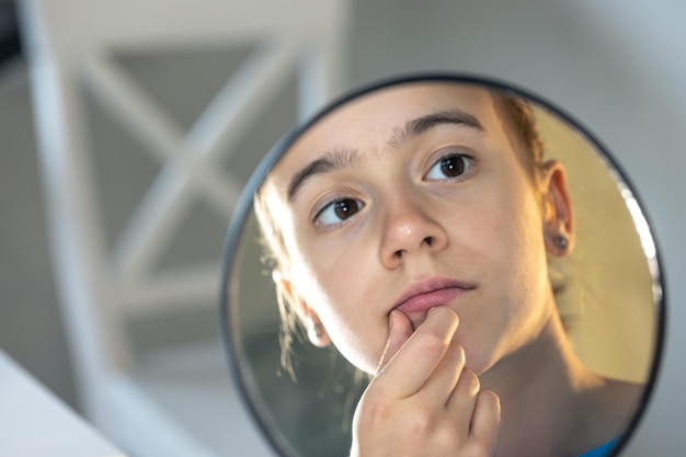 Free Photo a teenage girl looks thoughtfully at her reflection in the mirror