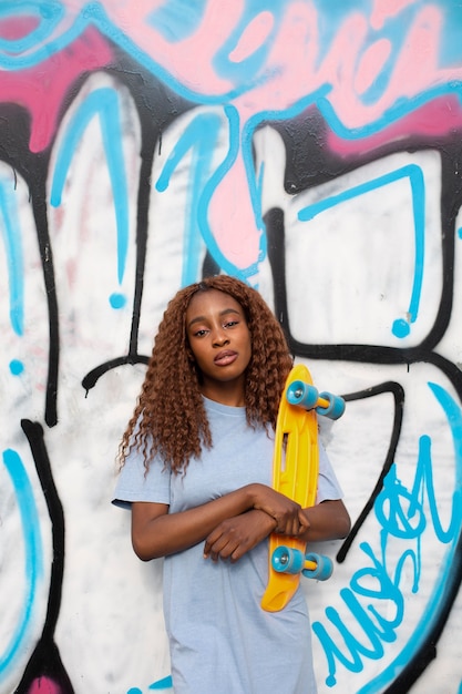 Teenage girl posing at park with skateboard