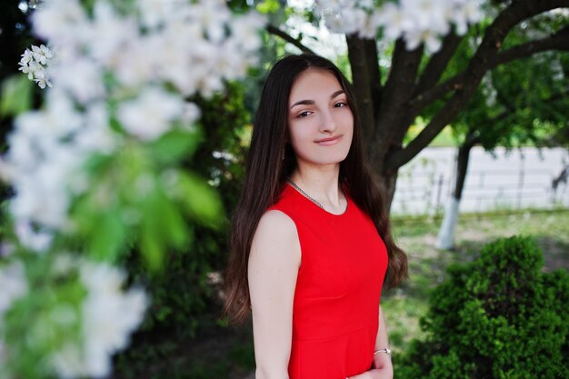 Teenage girl in red dress posed outdoor at sunny day