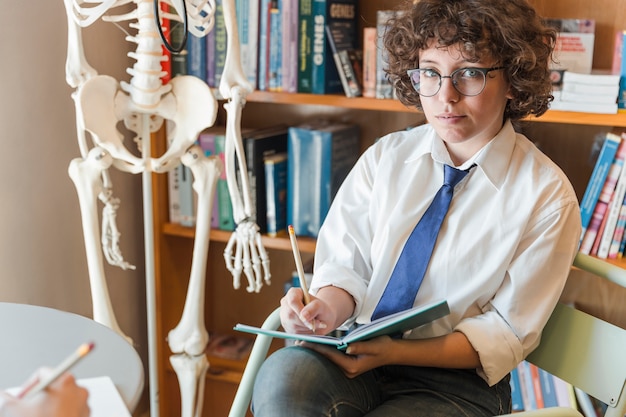 Teenage girl in uniform writing in notebook