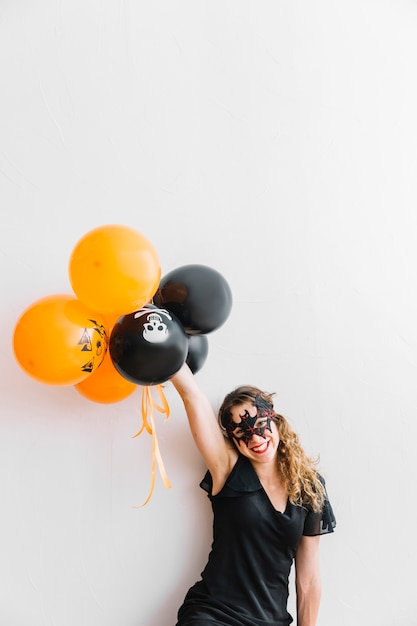 Free photo teenage girl with halloween grim holding orange and black air balloons