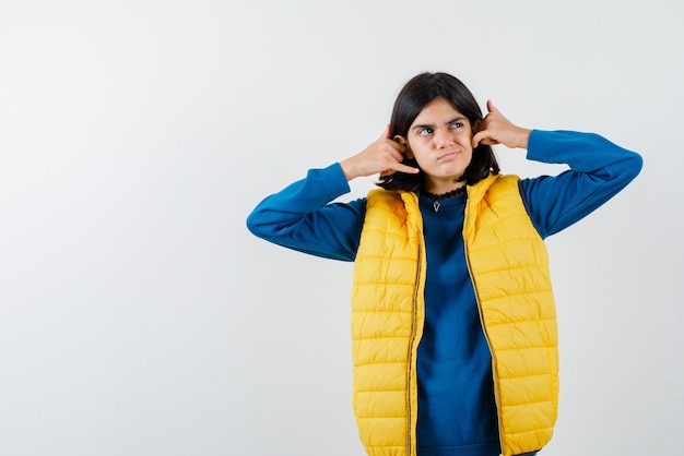 Free Photo teenage girl with a perplexed look on her face showing a call me hand gesture with both hands on white background