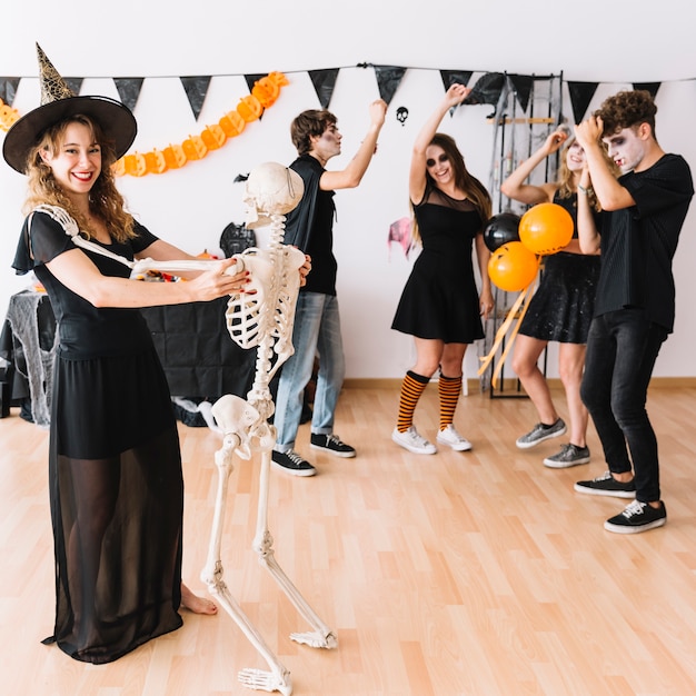 Free photo teenage halloween party with witch dancing with skeleton