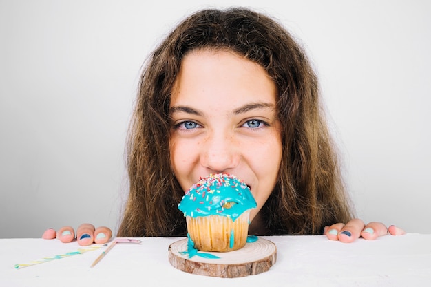 Teenager biting cupcake and looking at camera