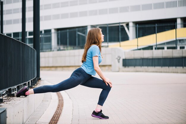 Teenager doing lunges near fence