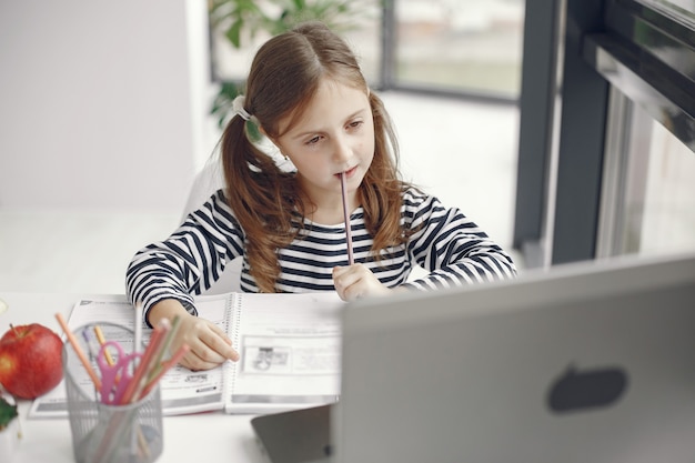 Teenager girl looking at laptop. Chiln at quarantine isolation period during pandemic. Home schooling. Social distancing. Online school test.