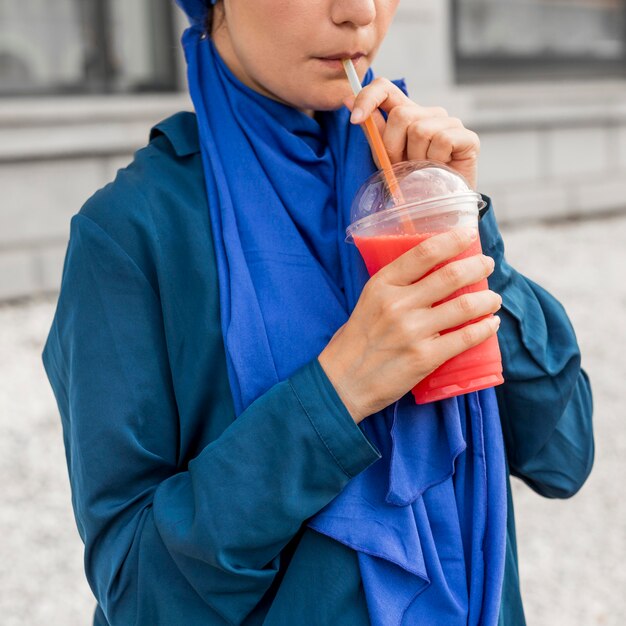 Teenager girl wearing blue clothes and drinking a smoothie