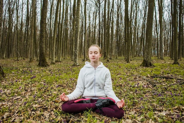 Free Photo teenager in lotus pose meditating in forest