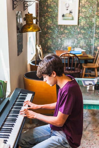 Free photo teenager playing piano in cozy cafe