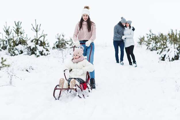 Teenager pulling sleigh with sister near parents