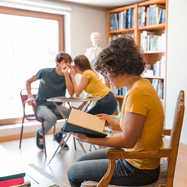 Free Photo teenager reading near gossiping classmates