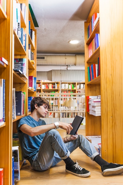 Free photo teenager relaxing with book in library