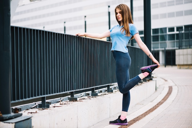 Free Photo teenager stretching leg near fence