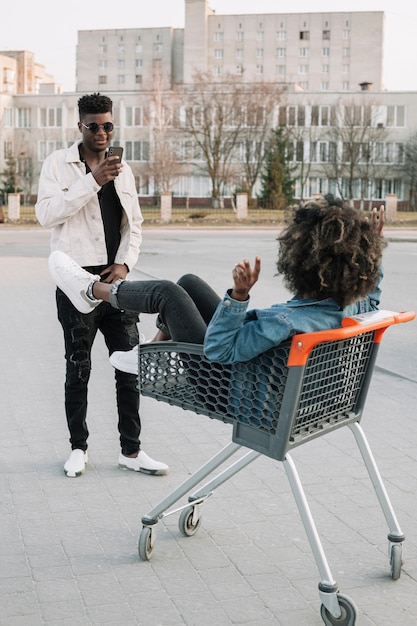 Teenager taking a picture of friend in shopping cart