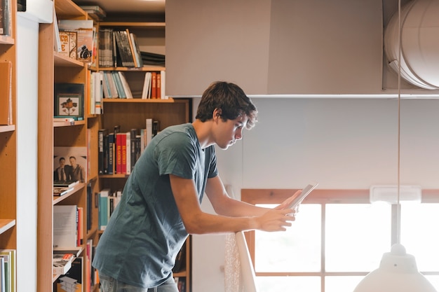 Teenager using tablet near railing in library