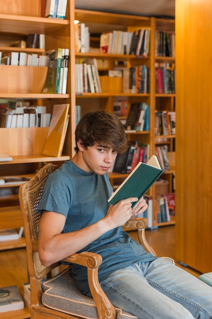 Teenager with book sitting in library