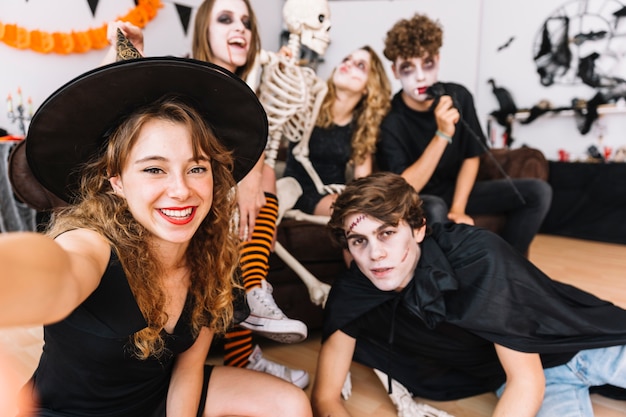 Free photo teenagers in halloween costumes doing selfie on floor