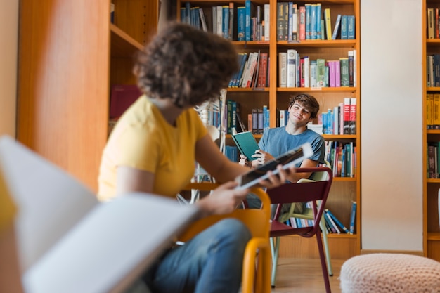 Free photo teenagers looking at each other in library