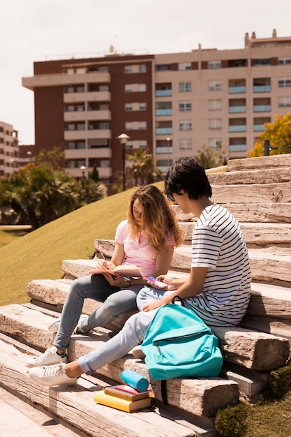 Free photo teenagers studying together on stairs in street