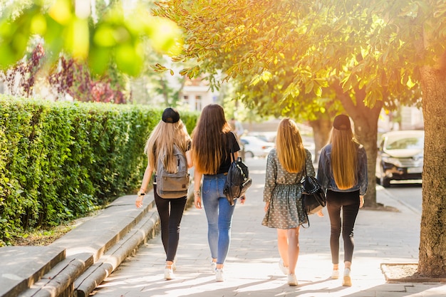 Free Photo teenagers with backpacks walking on street