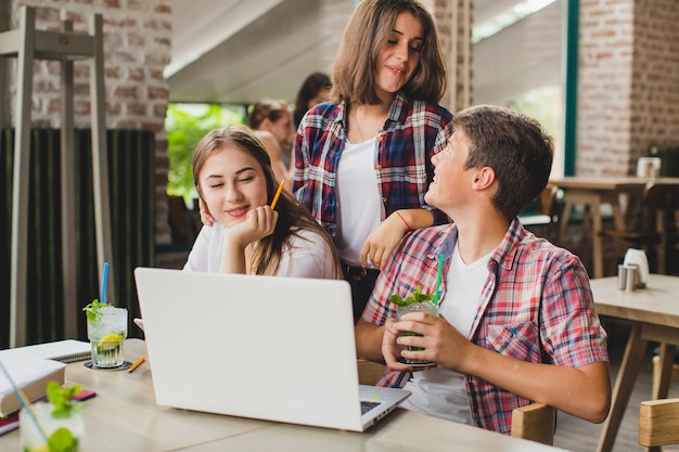 Teenagers with laptop spending time in cafe