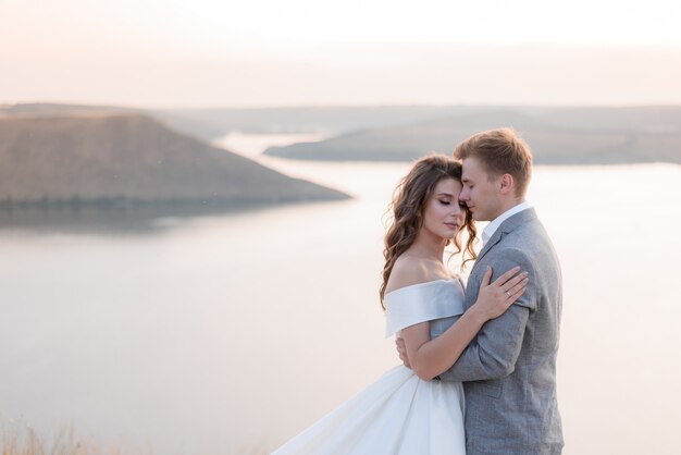 Tender bridal couple is hugging in front of the picturesque sea view