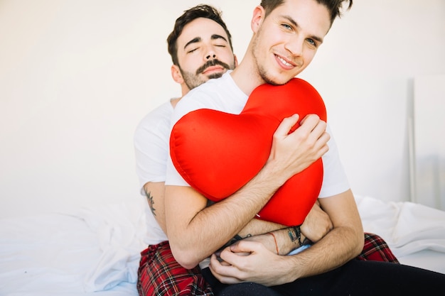 Tender gay couple embracing on bed