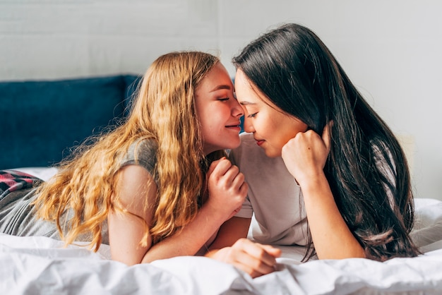 Tender lesbian couple lying on bed