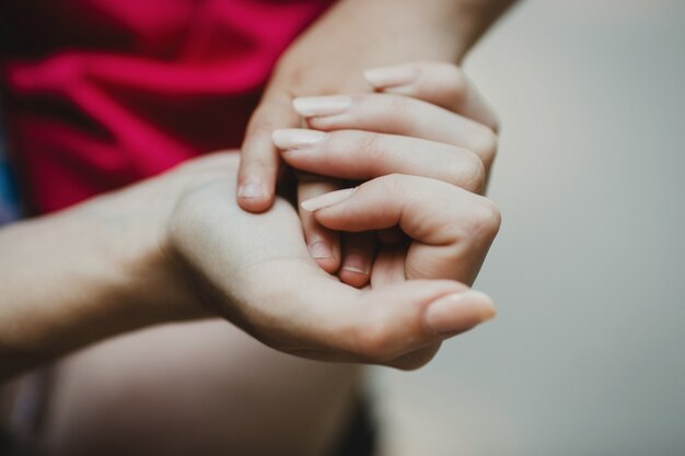 Tender mother's hand holds child's fingers on her palm