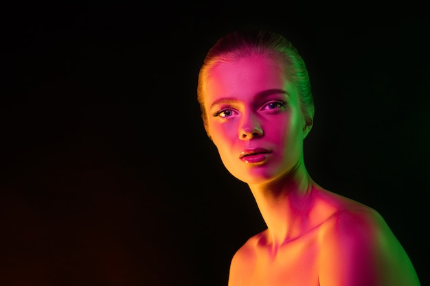 Free photo tender. portrait of female fashion model in neon light on dark. beautiful caucasian woman with trendy make-up and well-kept skin