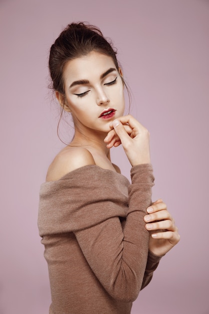 tender woman posing in profile with closed eyes on pink