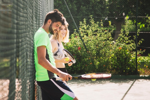 Tennis friends leaning at fence