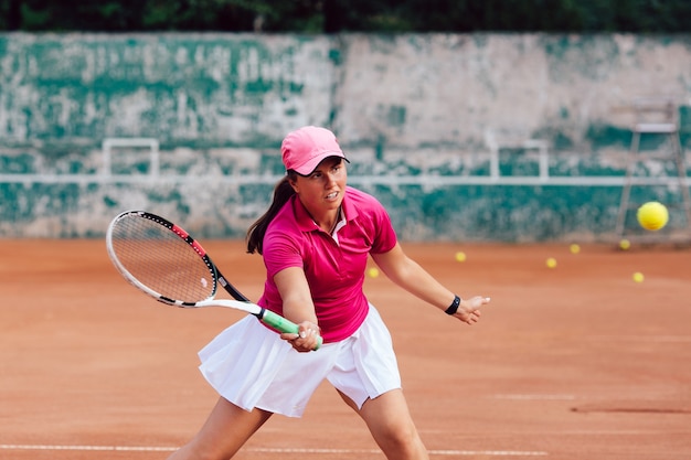 Tennis player. Female player dressed in pink skirt and white blouse, playing tennis on court