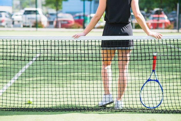 Tennis player with racket standing behind the net