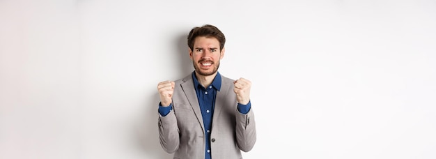 Free photo tensed businessman feeling nervous and pressured clenching fists and teeth staring at camera making